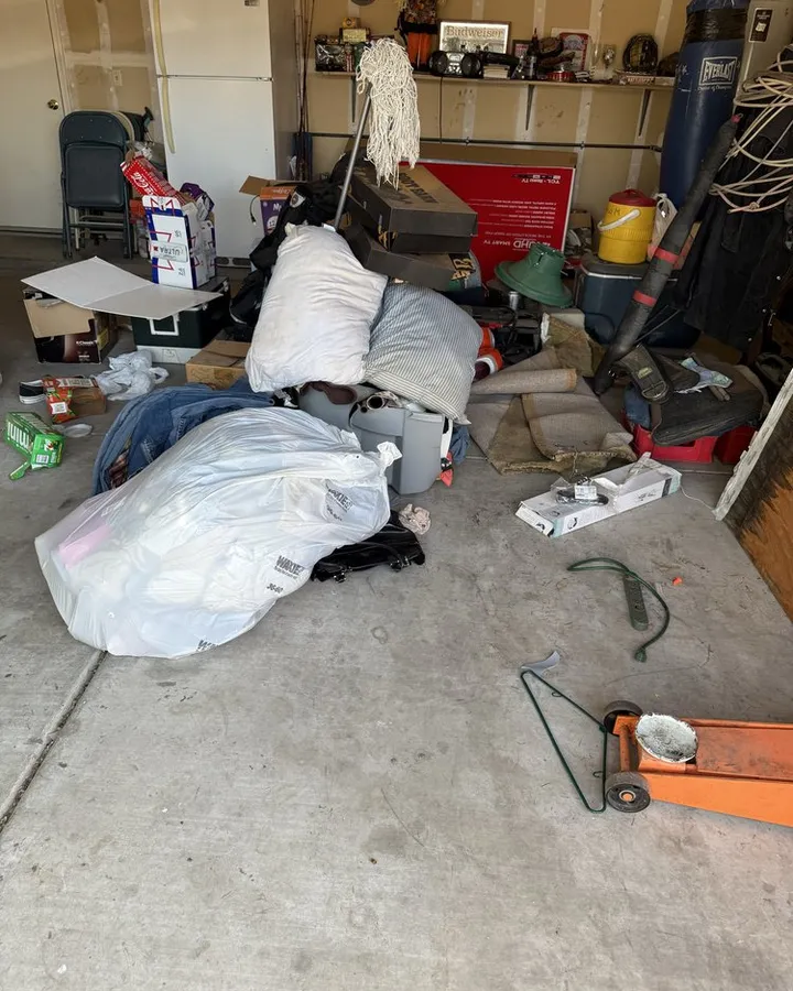 Garage floor covered in bags, boxes, and old household items.