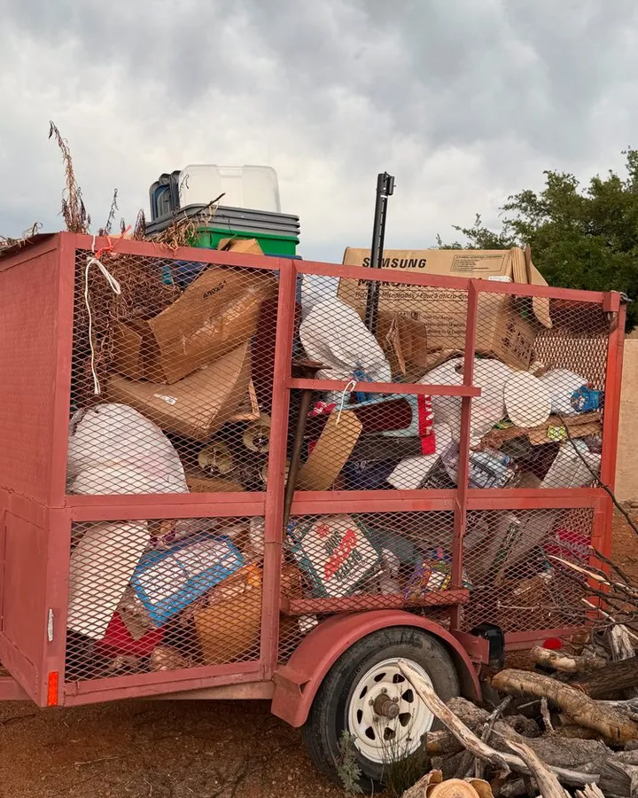 Trailer loaded with household junk, boxes, and branches.